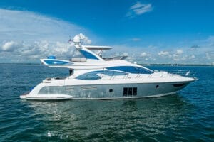 Modern luxury yacht sailing on clear blue waters under a partly cloudy sky, representing Miami yacht rentals and charters.