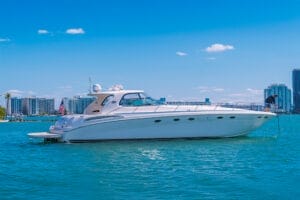 Luxury yacht rental in Miami offers island-hopping and day cruises. White yacht anchored on turquoise waters with Miami skyline and clear blue sky in the background. Experience premium yachting with Wonder Yachting.