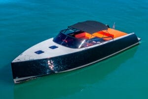 Luxurious black yacht with orange interior and American flag, cruising in clear blue Miami waters, ideal for family and celebrity experiences.